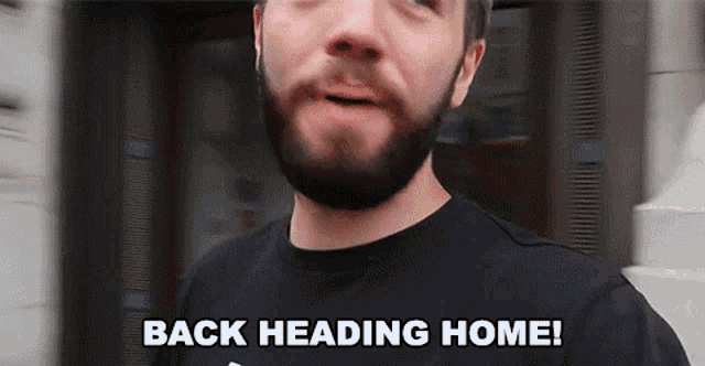 a man with a beard wearing a black shirt says " back heading home "