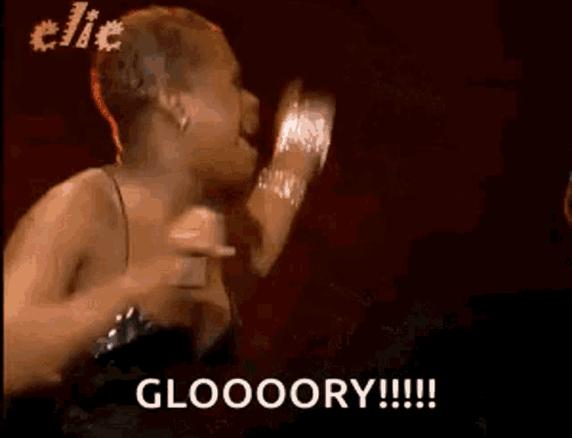 a woman in a black dress is singing into a microphone and says gloooory .