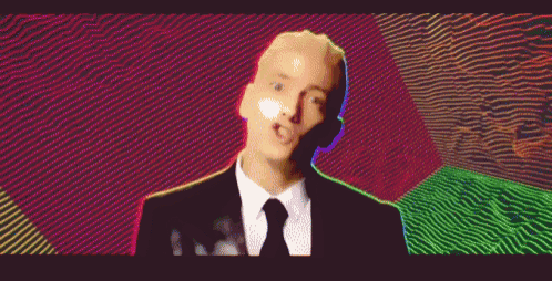 a man in a suit and tie is standing in front of a colorful background and making a funny face .