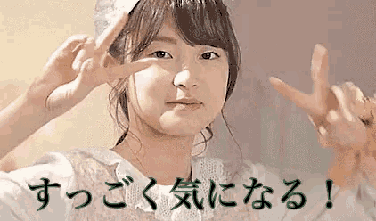 a girl is making a peace sign with her hands in front of her face .