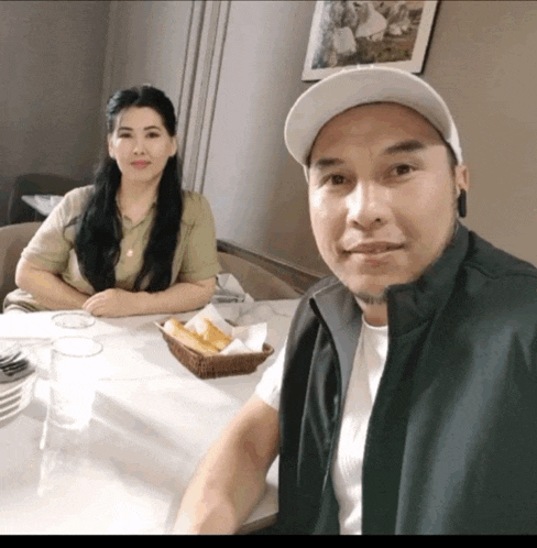 a man and a woman sit at a table with a basket of bread