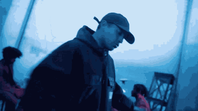 a blurry picture of a man wearing a hat and a hoodie that says ' supreme ' on it