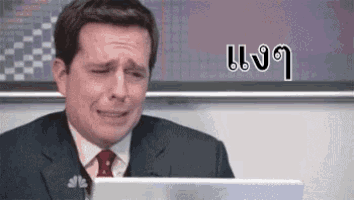 a man in a suit and tie is crying while sitting at a laptop computer .