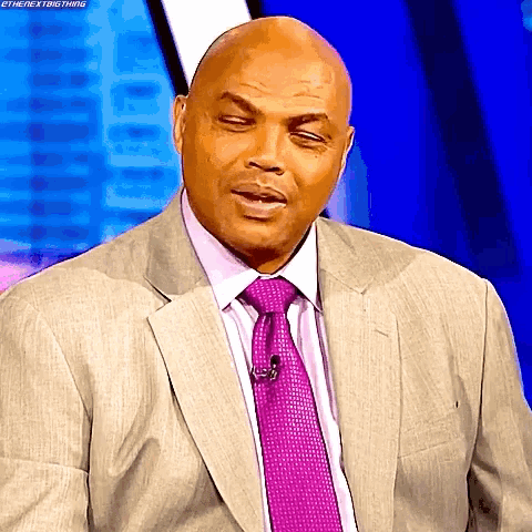 a bald man in a suit and tie is making a funny face ..
