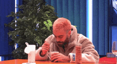 a man is sitting at a table eating a cup of coffee with a spoon