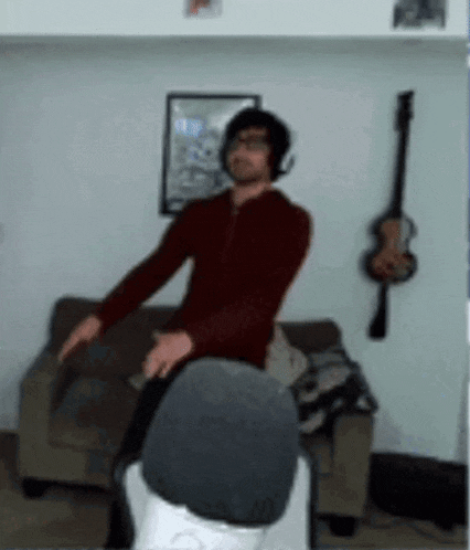 a man wearing headphones is dancing in a living room next to a guitar .