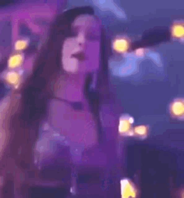 a woman in a purple dress is dancing in front of a sign that says 5