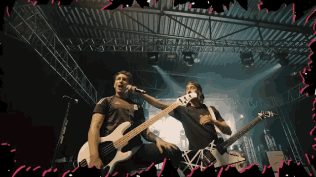 a man singing into a microphone while another man plays a bass guitar