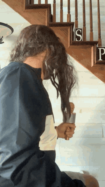 a man brushes his hair in front of a set of stairs with letters s and p