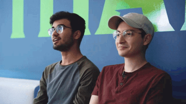two men are sitting in front of a wall that has the word titan on it