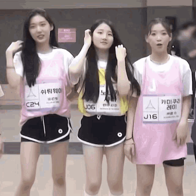 three girls are standing next to each other wearing pink shirts and shorts