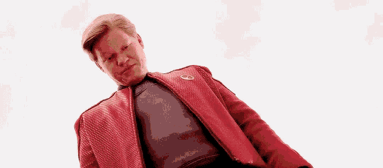 a man in a red jacket is laying down on the floor .