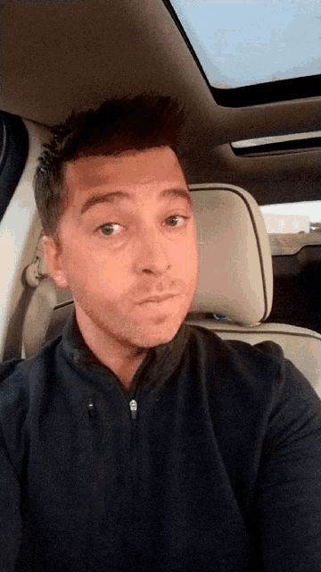 a man is sitting in the back seat of a car and looking at the camera