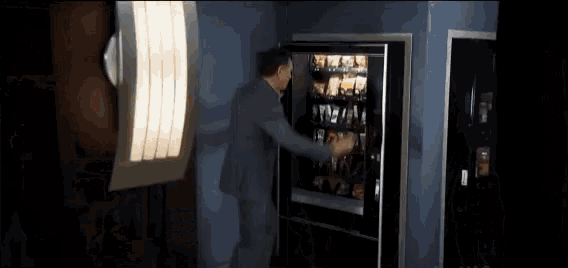 a man reaches into a vending machine in front of a tv 14 sign