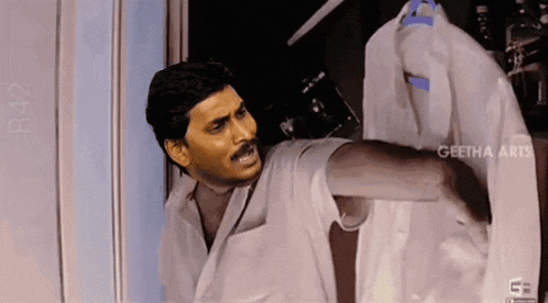 a man in a white coat is holding a white shirt .