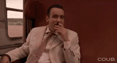 a man in a suit and tie is sitting on a train .