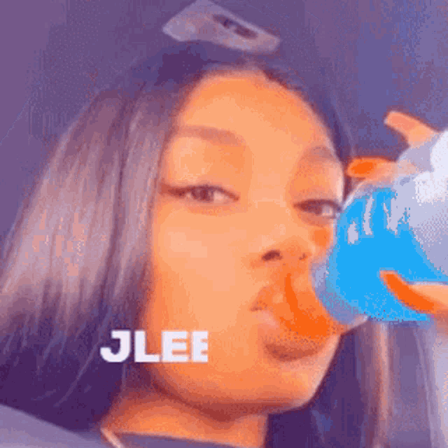 a woman is drinking a bottle of blue liquid from a bottle .