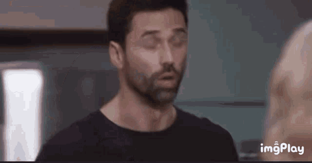 a man with a beard is making a funny face while looking at a woman .