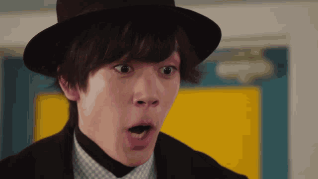 a man wearing a hat and a suit makes a surprised expression
