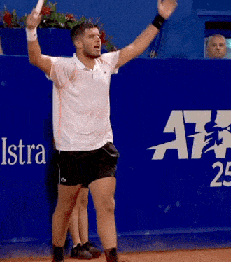 a man holding a tennis racquet in front of a blue wall that says iskra