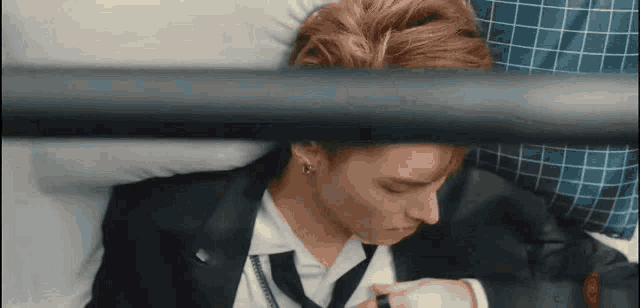 a man in a suit and tie is laying on a bed and looking at his watch .