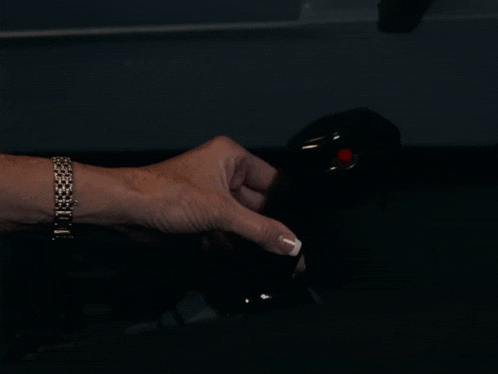 a woman 's hand is holding a black object with a red button