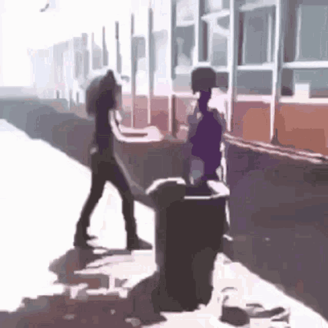a man and a woman are standing next to a trash can on a sidewalk .