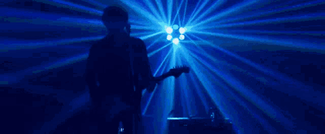a man is playing a guitar in front of a blue light