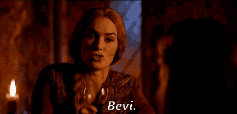 a woman is sitting at a table holding a glass of wine .