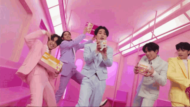 a group of young men in pink suits are holding boxes of mcdonald 's