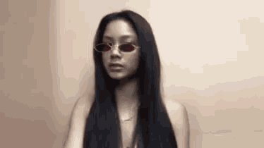 a woman with long black hair wearing red sunglasses and a necklace .