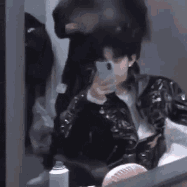 a man in a leather jacket is taking a selfie with his cell phone .