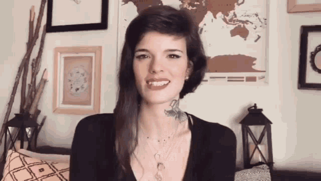 a woman with a tattoo on her neck is smiling in front of a map