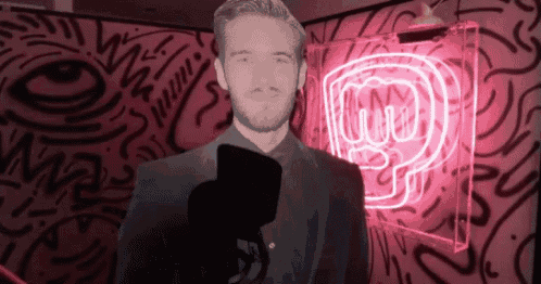 a man in a suit stands in front of a microphone in front of a neon sign that has the letter p on it