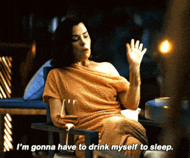 a woman sitting in a chair with a glass of wine says i 'm gonna have to drink myself to sleep ..