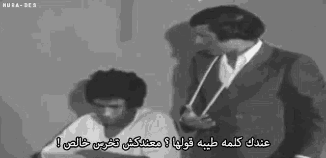 two men are standing next to each other in a black and white photo with arabic writing .