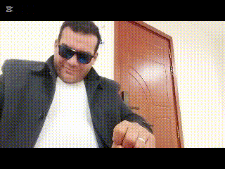 a man wearing sunglasses and a white shirt is pointing to the camera