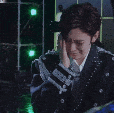 a man in a suit is crying with a ring on his finger in front of a green background
