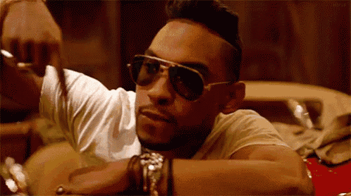 a man wearing sunglasses and a white shirt is laying on a red chair .