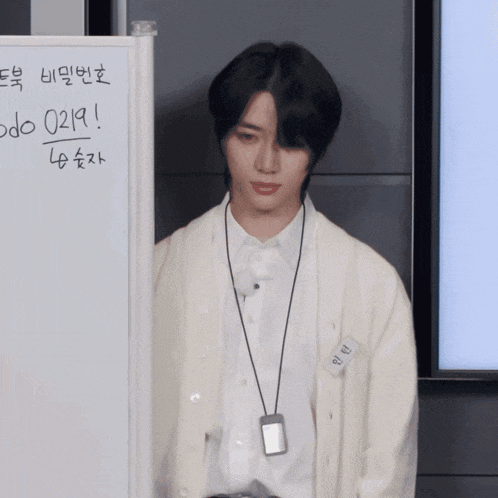 a young man stands in front of a white board with the number 0219 on it