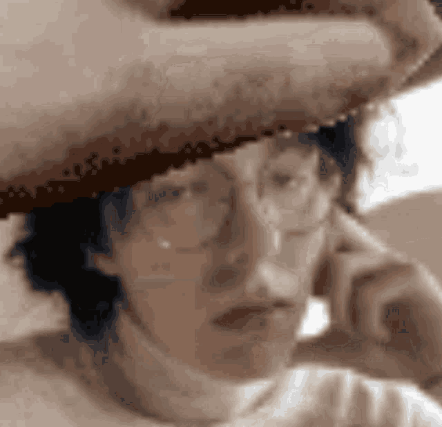 a woman wearing glasses and a hat is talking on a phone