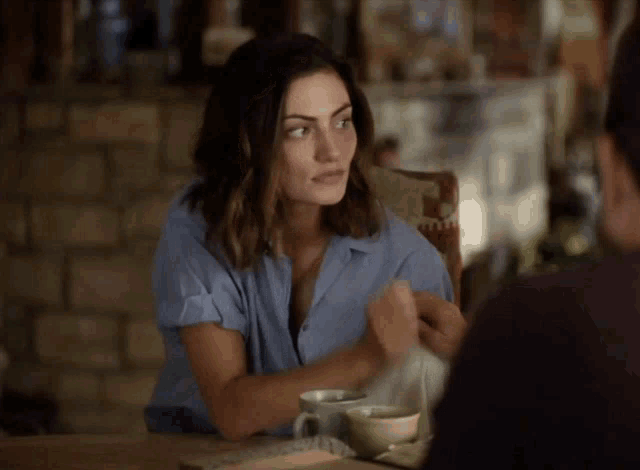 a woman in a blue shirt is holding a man 's hand