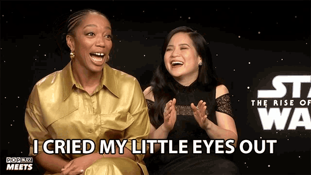 two women laughing in front of a star wars poster that says " i cried my little eyes out "