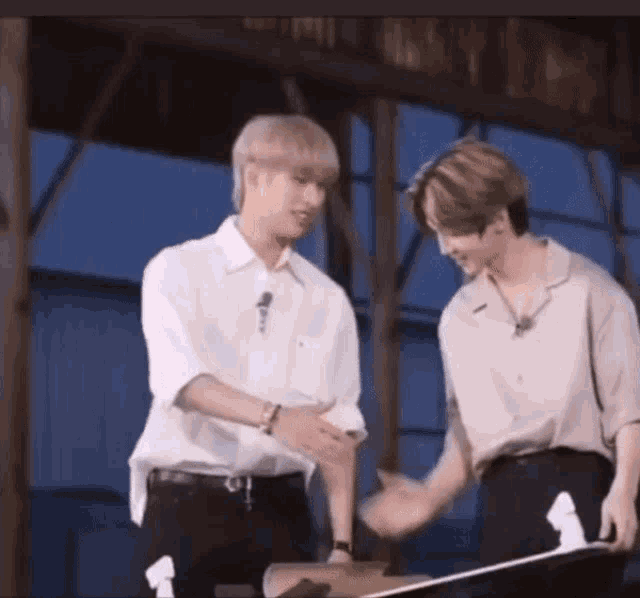 two men are shaking hands while standing next to each other in a room .