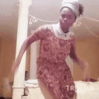 a woman in a pink dress and turban is dancing in a room with columns .