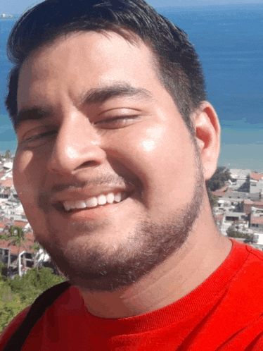 a man with a beard wearing a red shirt is smiling