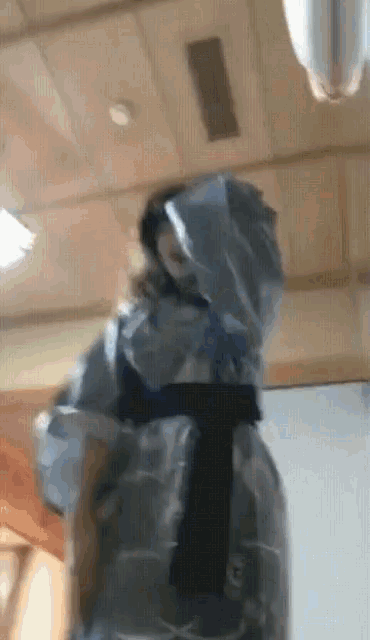 a person wrapped in plastic is standing in a room with a wooden ceiling
