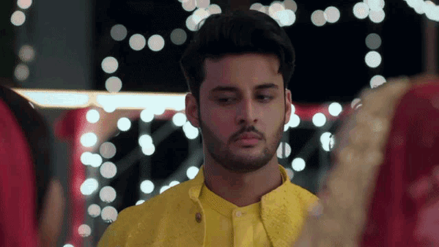 a man in a yellow shirt is looking at a woman