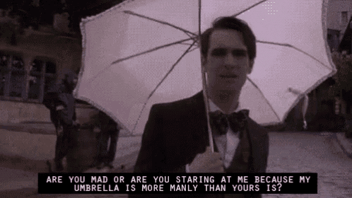 a man in a suit and bow tie is holding a white umbrella in the rain .