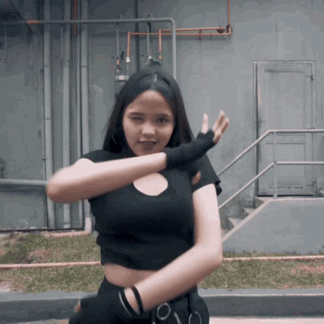 a woman in a black top and black gloves is dancing